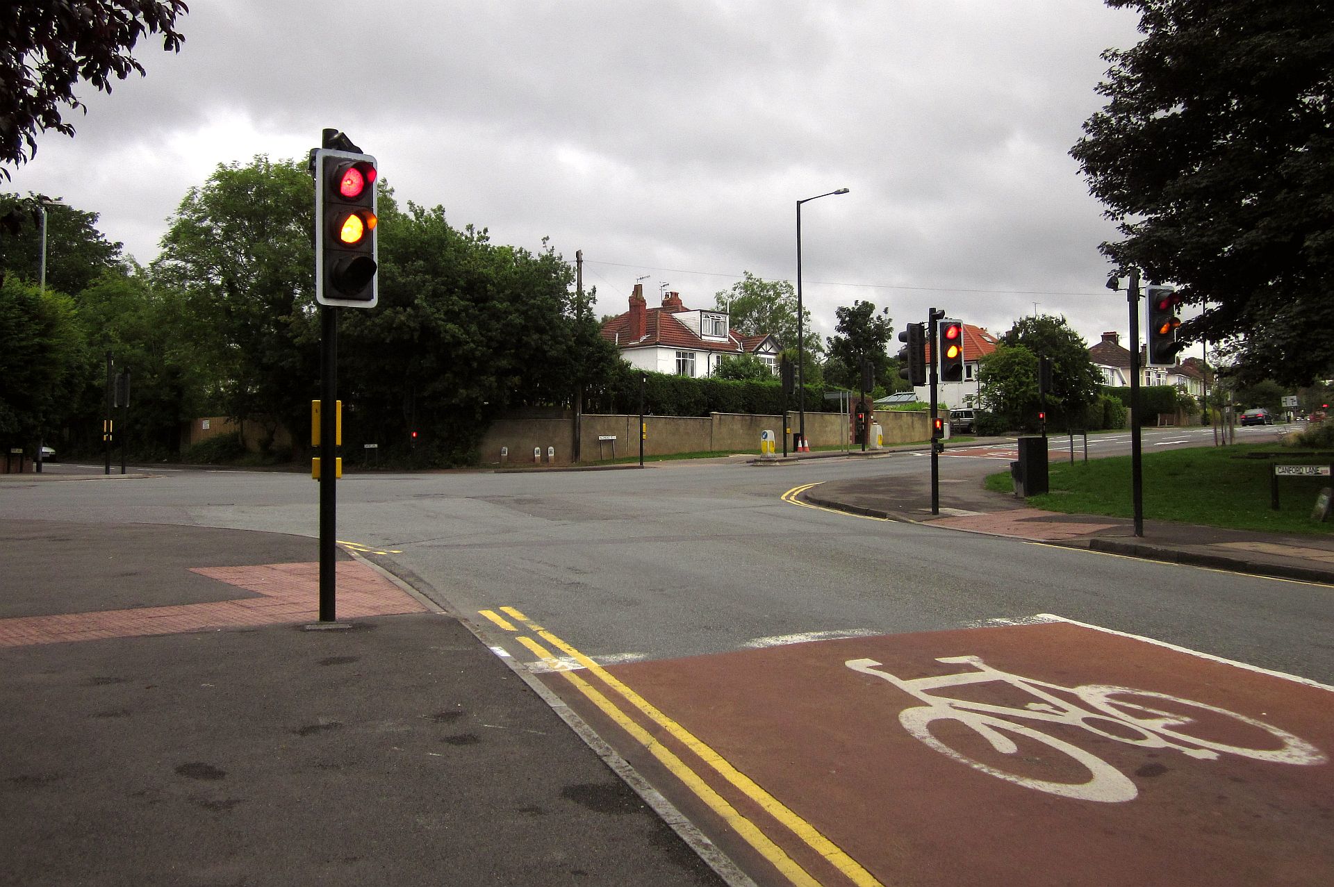A UK road junction traffic light showing red and amber, about to turn green.